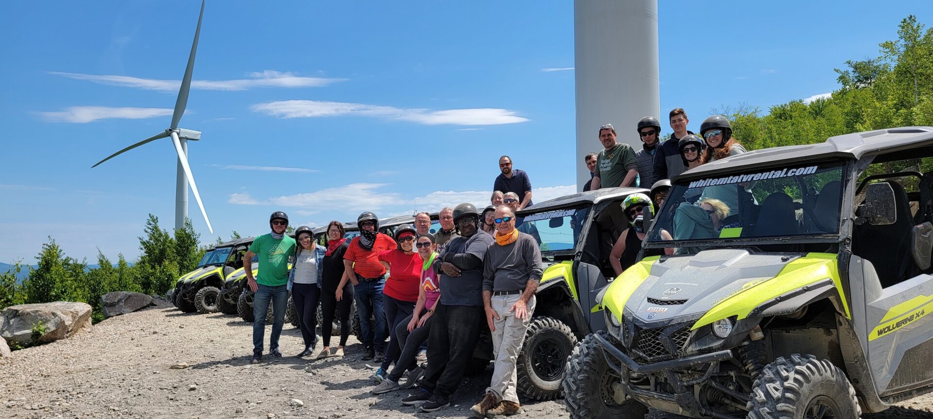 Group of people posing for picture near cars